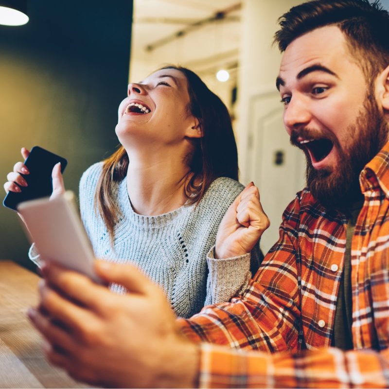 Woman and man using smartphones with looks of excitement