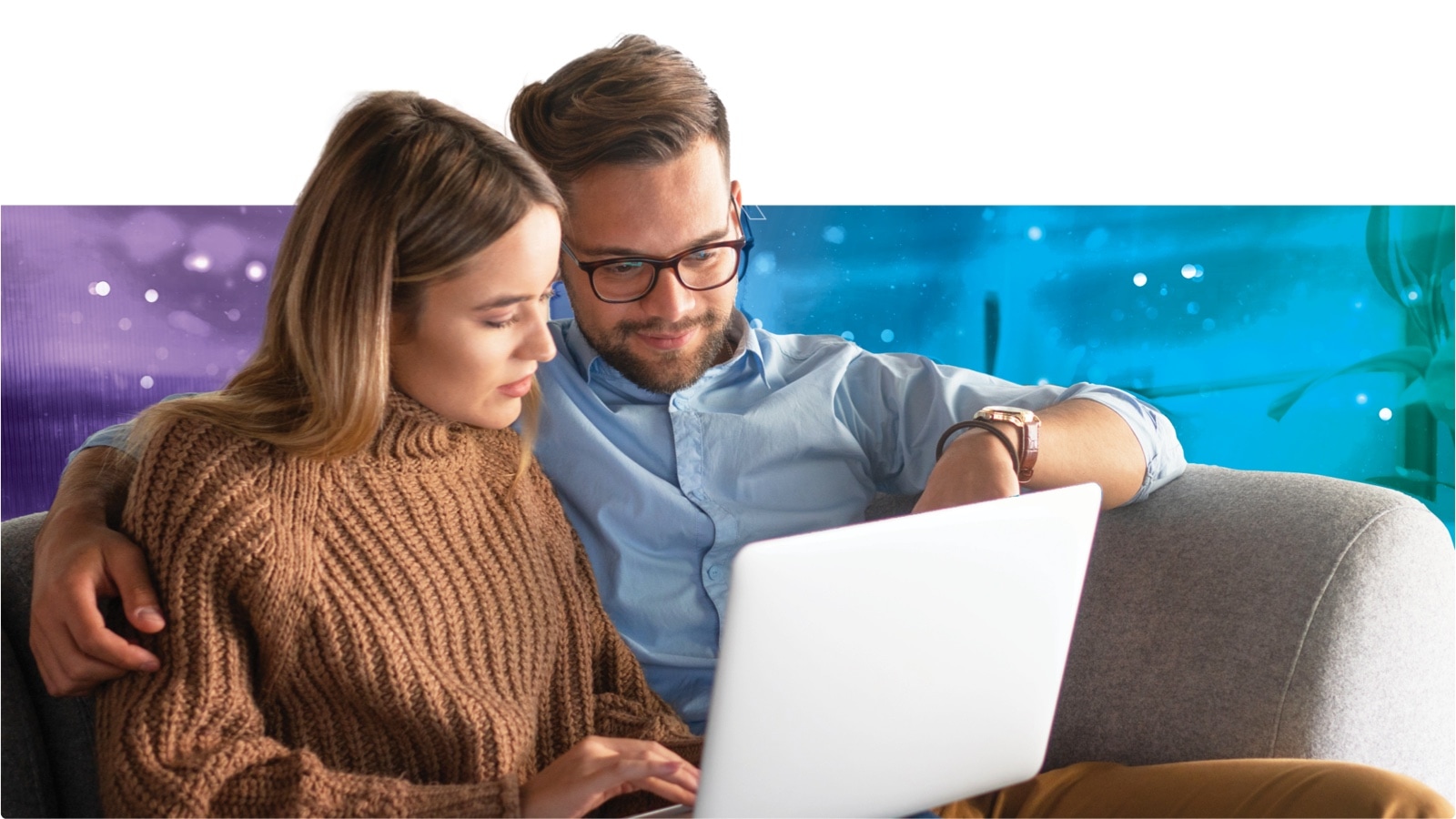 A man and woman sitting on a couch using a laptop together