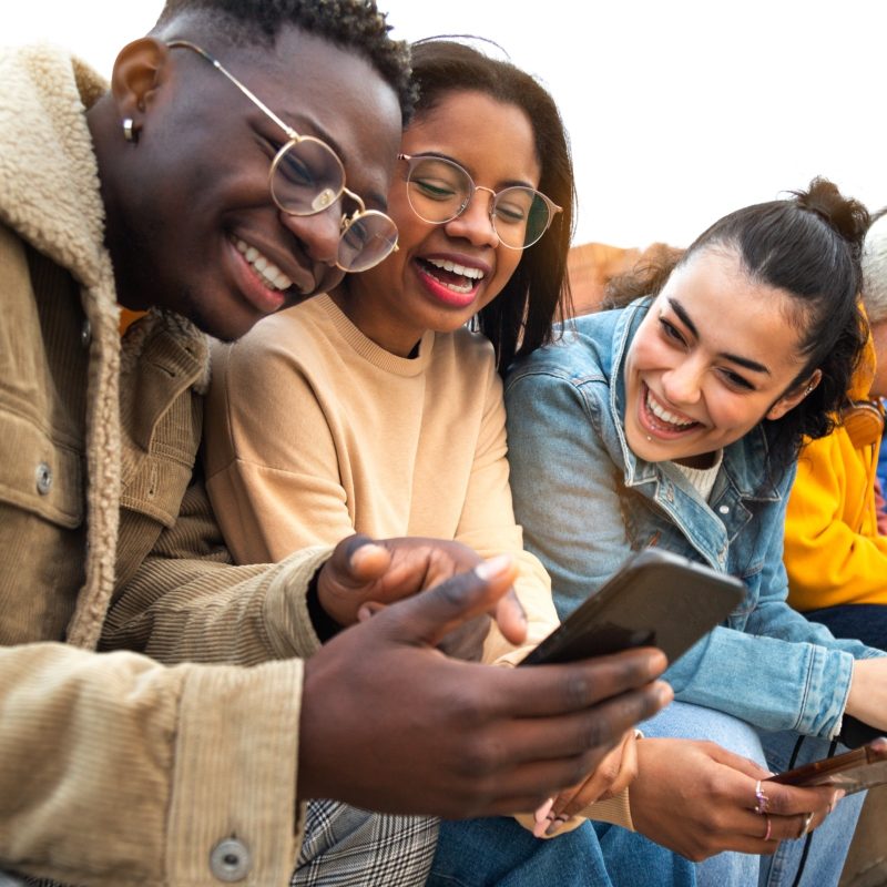A group of youths laughing while looking at a smartphone